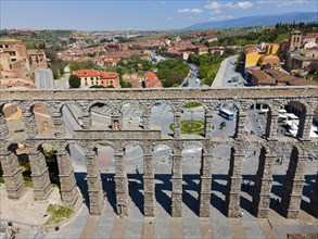 Aerial view of a historic city area with an aqueduct and various buildings as well as a busy