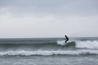 A surfer enjoys the high waves at Strandhill along Wild Atlantic way on the west coast of Ireland.,