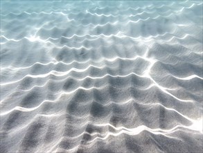 Wave patterns and light reflections in the clear water over a sandy bottom. Calm and peaceful