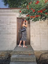 Young woman enjoys a beautiful summer day in vacation standing at the threshold of a door smelling