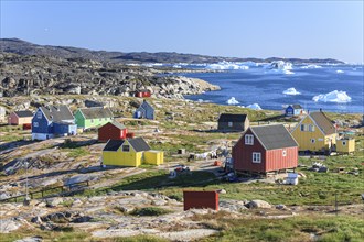 Typical Greenlandic houses, Inuit settlement in front of icebergs, Qeqertaq, Disko Bay, West