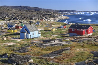 Typical Greenlandic houses, Inuit settlement in front of icebergs, Qeqertaq, Disko Bay, West