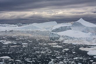 Icebergs in a fjord against a cloudy sky, summer, Ilulissat Icefjord, Disko Bay, West Greenland,