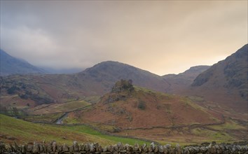 View of the English mountain landscape with a stone wall in front of it in the evening light,