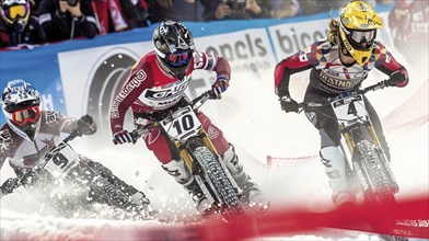 Three cyclists competing in a snow race, moving quickly with intense focus, wearing protective gear