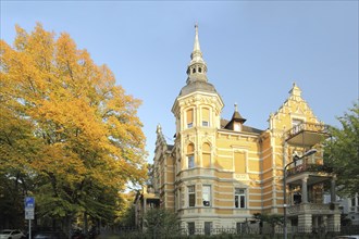 Historicist villa built in 1897 with corner turrets and decorations, tree, autumn atmosphere,