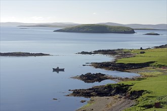 Peaceful coastal landscape with views of calm waters, small islands and a boat in the distance,