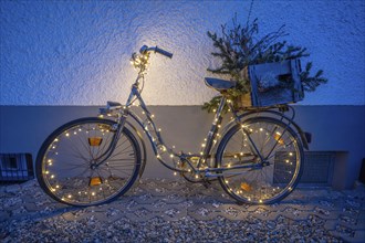 Illuminated bicycle leaning against the wall of a house during the Advent season, Bavaria, Germany,