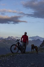 Mountain biker with headlamp, with trail dog in the evening, man with his Vizsla, panoramic trail,