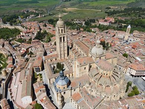 Panoramic view of a medieval city with a prominent church surrounded by green countryside and