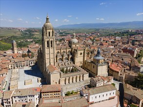 Large church in a medieval town, surrounded by red roofs and historic buildings, under a blue sky