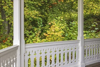 White wooden railing on a terrace with joinery and autumn colors in the forest