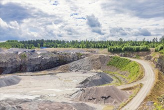 Road to a industrial open pit with gravel piles in the forest