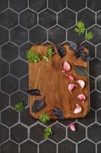 Overhead composition with place for text with wooden chopping board with basil, garlic and cilantro