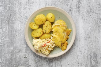 Overhead view of baked pork fillet with melted cheese and onion served with fried potato and