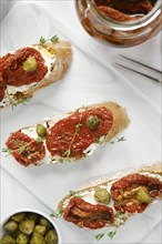 Overhead close-up view of bruschetta with sun-dried tomatoes and capers on kitchen table