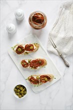 Overhead view of bruschetta with sun-dried tomatoes and capers on kitchen table