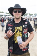 Festival visitor with a French fries fork (as a hand sign and in the waistcoat) at the Wacken Open