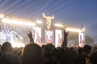 A festival visitor shows the devil's salute in front of the two main stages Faster and Harder at