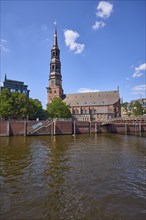 Customs canal with main church St. Katharinen against blue sky with cumulus clouds, Speicherstadt,