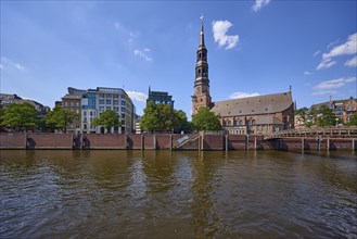 Customs canal with main church St. Katharinen against blue sky with cumulus clouds, Speicherstadt,