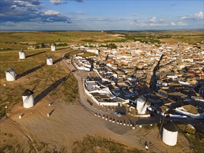 Aerial view of windmills near a village in sunny weather with blue sky and clouds. The white