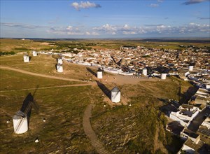 Windmills scattered on a hill near a village in sunny weather with blue skies and clouds. The