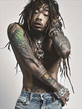 A shirtless, tattooed man with dreadlocks, wearing jeans and multiple pieces of jewelry, exudes