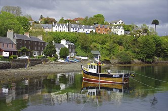 Colourful houses and fishing boats on a small harbour with calm water, Portree, Isle of Skye,