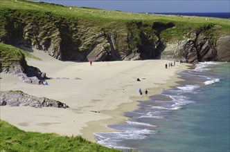 Sandy beach beach with cliffs in the background and people along the coast, Blasket Islands,