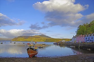 Harbour with colourful houses on the shore, several boats in the water and a wide, cloudy sky