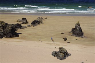 People walking on a beach with big rocks and waves in the background, Durness, Scotland, Great