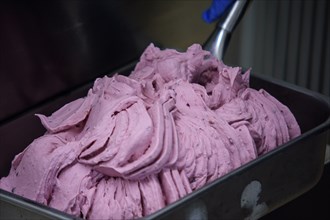 Close up of a professional ice cream machine mixing a delicious pink fruit flavor ice cream, the