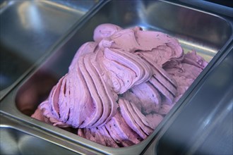 Close-up of pink ice cream being prepared in a stainless steel tray