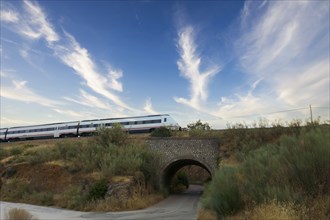 Moving train passing over a tunnel, cloudy sky in the background