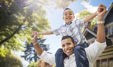 Happy father and son riding piggyback in front yard of their house