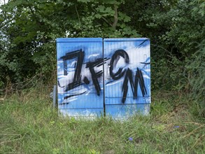 Blue and white graffiti 1. FCM (football club 1.FC Magdeburg) on an electricity box at Jersleber