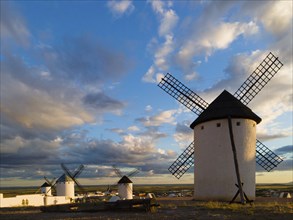 Several windmills stand in an open landscape under a dramatic sky at sunset, Windmills, Campo de