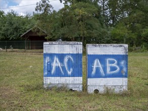 Electricity boxes with the spray-painted letters AC and AB on Lake Jersleben next to a campsite,