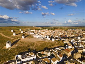 Aerial view of a village with several windmills and houses under a blue sky with clouds, aerial