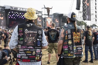 Metalheads with patches in front of the main stages at the Wacken Open Air in Wacken. The