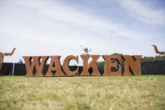 Festival visitor Hanna sits on the Wacken lettering at the Wacken Open Air in Wacken. The