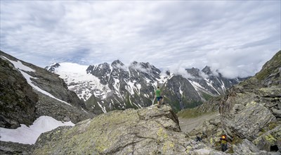 Mountaineer in a rocky saddle, Lapenscharte with view of mountain peaks and glacier into the valley