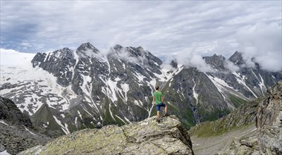 Mountaineer in a rocky saddle, Lapenscharte with view of mountain peaks and glacier into the valley