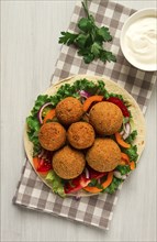 Tortillas, wrapped falafel balls, with fresh vegetables, vegetarian healthy food, on a wooden white