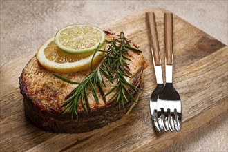 Salmon steak, fried, on a cutting board, top view, rosemary, lemon and lime, homemade, one serving,