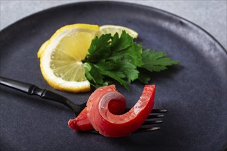 Chum salmon, cold smoked, on a fork, with lemon and parsley, top view, close-up, no people