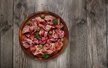 Assortment, sliced meat appetizer, prosciutto, salami and ham, with olives, on a wooden board,