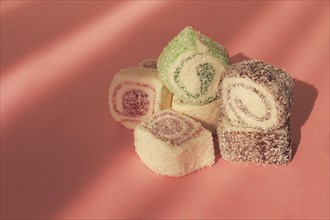 Traditional Turkish delight, rols shape, in coconut flakes, on pink background, sunlight,