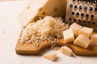 Grated cheese, Maasdam, on a cutting board, grater and cheese knife, close-up, no people